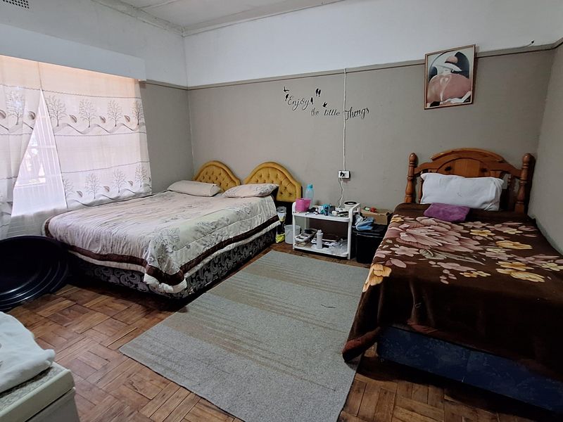 A spacious bedroom featuring original parquet flooring, high ceilings, and large windows allowing for natural light.