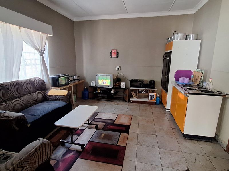 An open-plan living and kitchen area featuring tiled flooring, basic cabinetry, and a functional layout suitable for compact living.