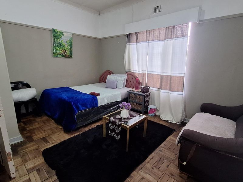 A bedroom featuring original parquet flooring and a high ceiling with visible signs of wear and maintenance requirements.