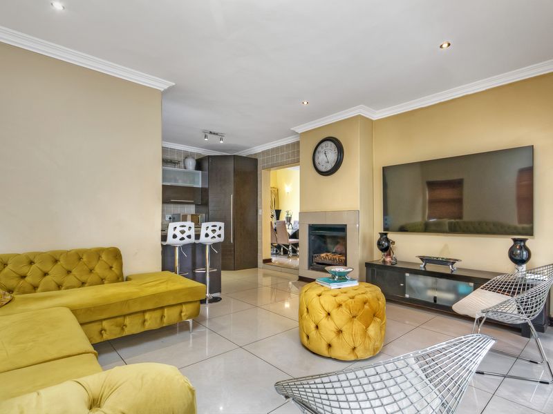 Open-plan living area featuring tiled floors, recessed lighting, crown molding, and a built-in fireplace, seamlessly connecting to the kitchen space.