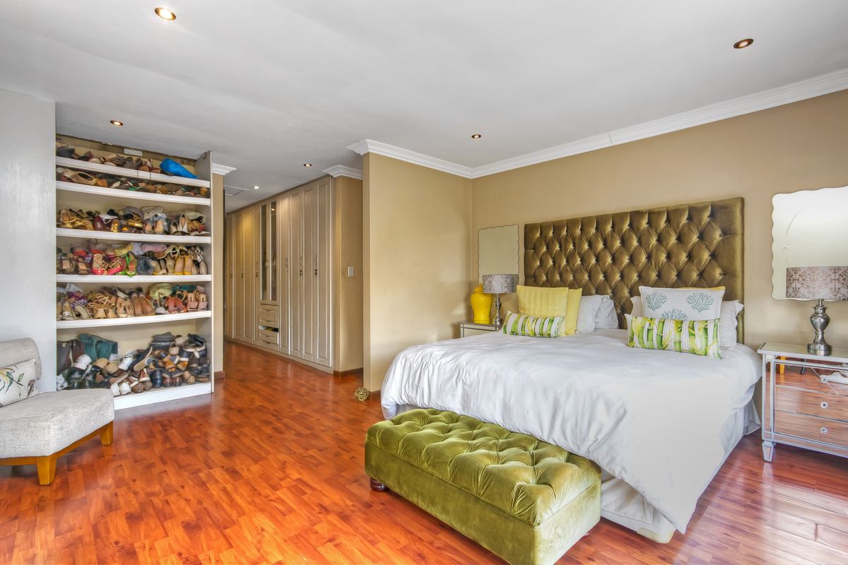 Spacious bedroom featuring warm wooden flooring, extensive built-in cabinetry, open shelving for storage, and recessed ceiling lighting.