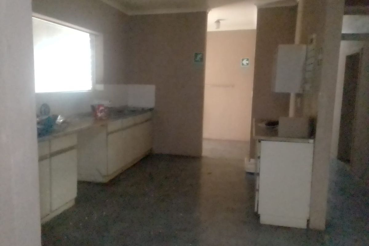 A basic, unfinished kitchen area featuring built-in cabinetry and a sink, requiring significant renovation and modernization to reach its full potential.