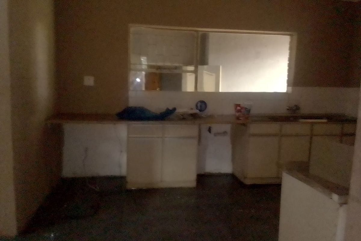 A dated kitchen space featuring basic cabinetry and a large window, requiring significant renovation and modernization to reach its full potential.