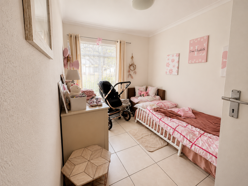 A well-maintained bedroom featuring neutral tiled flooring, security bars on the window, and classic cove cornicing.