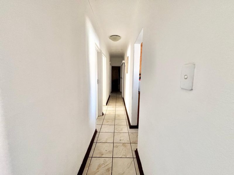 A clean, neutral hallway featuring tiled flooring and access to multiple rooms, providing a functional transition space within the townhouse.