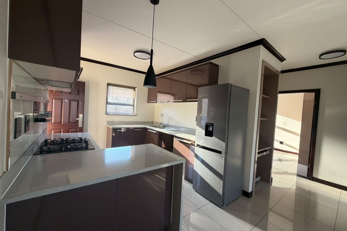 Modern kitchen featuring high-gloss cabinetry, stone countertops, gas hob, and tiled flooring, offering a clean and functional workspace.