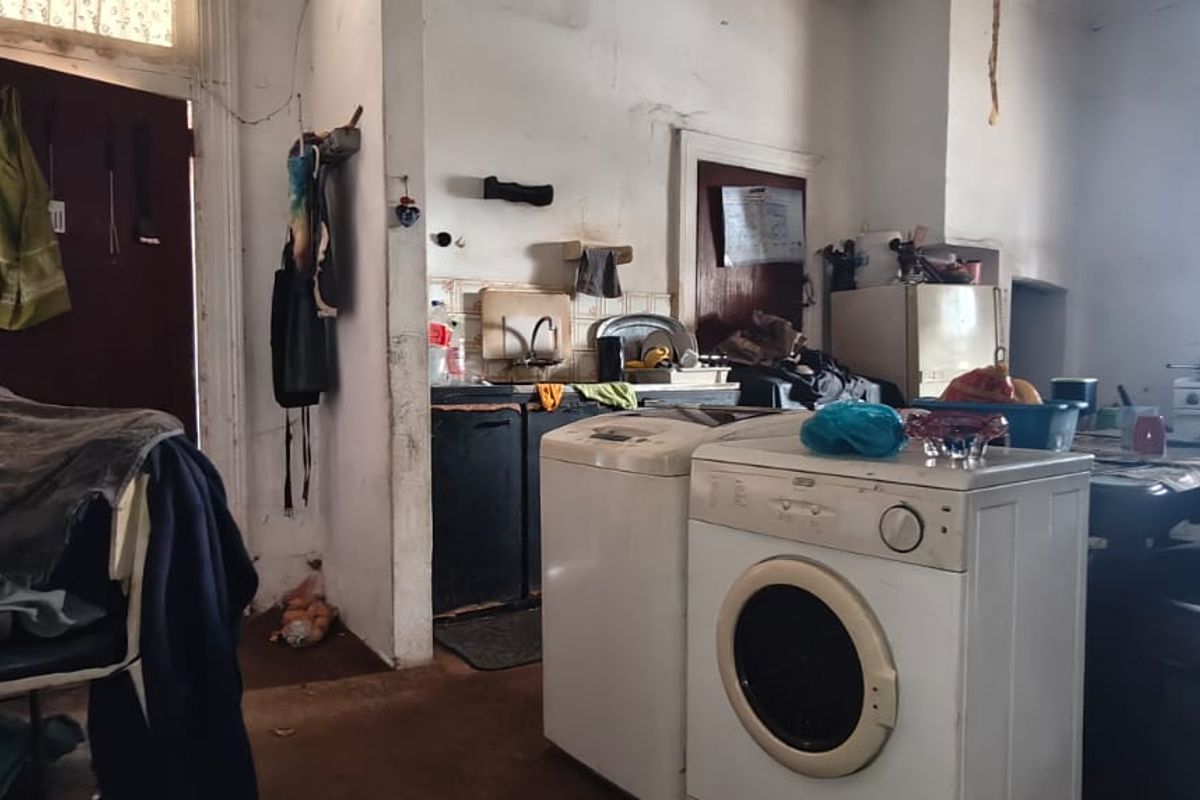 A dated kitchen area requiring significant renovation, featuring original cabinetry, worn wall finishes, and a functional layout with potential for modernization.