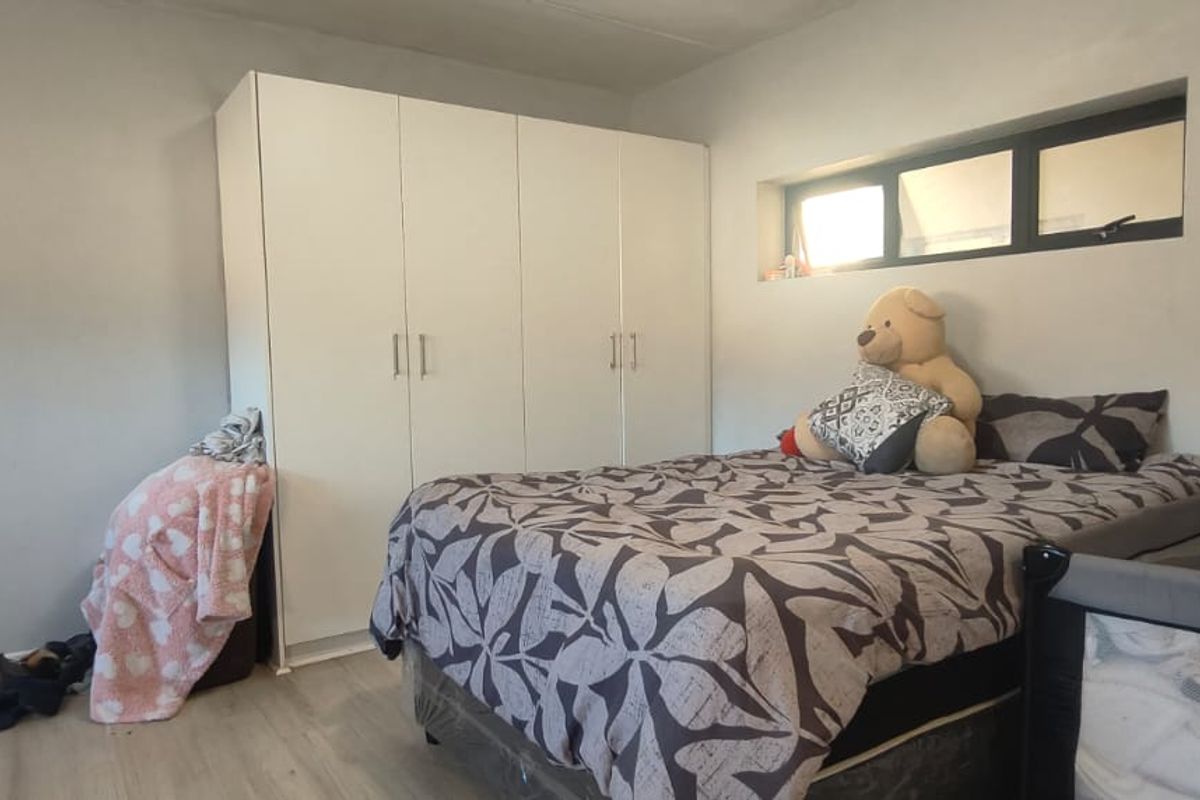 A bedroom featuring a large white built-in wardrobe and a horizontal clerestory window, providing functional storage and natural light.