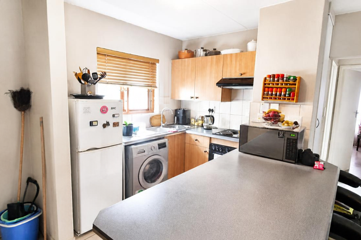 Functional kitchen featuring wooden cabinetry, laminate countertops, a breakfast bar, and integrated appliances, offering a practical layout for daily cooking and dining.