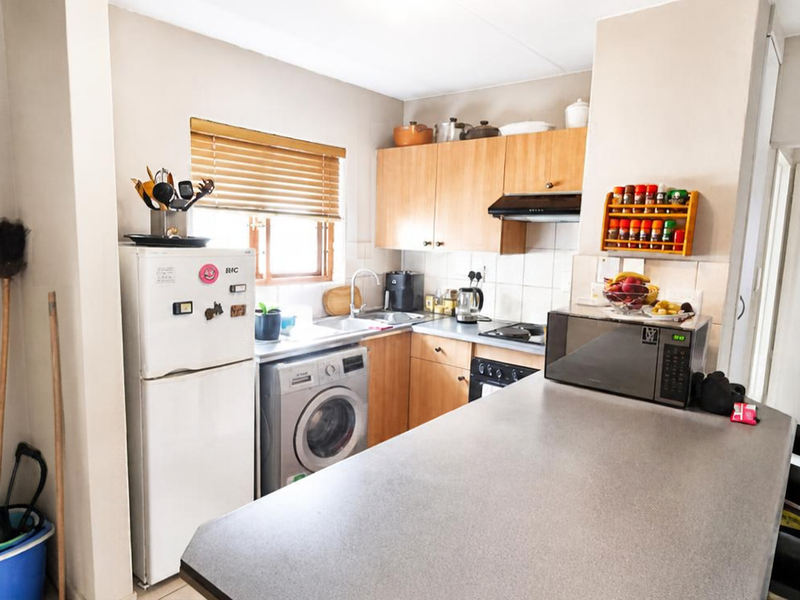 Functional kitchen featuring wooden cabinetry, laminate countertops, a breakfast bar, and integrated appliances, offering a practical layout for daily cooking and dining.