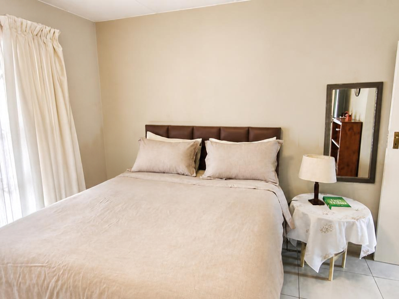 A well-lit bedroom featuring neutral wall tones, tiled flooring, and a sliding glass door providing access to the exterior.