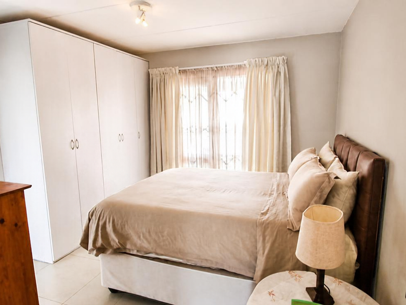 A well-maintained bedroom featuring neutral walls, tiled flooring, and ample built-in cupboard storage, creating a clean and functional living space.
