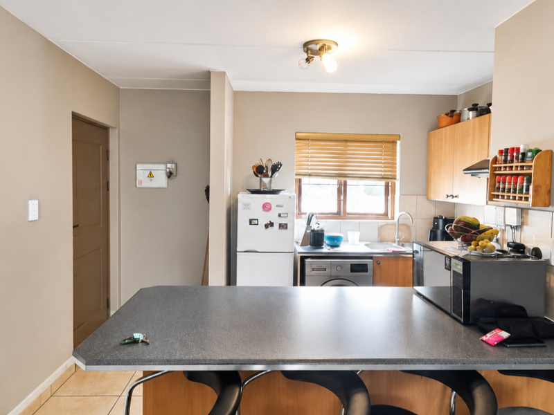 Functional kitchen featuring laminate countertops, built-in cabinetry, tiled backsplash, and a breakfast bar area, providing a practical layout for daily use.
