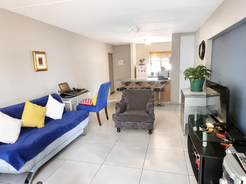 Open-plan living area featuring tiled flooring and a breakfast bar connecting to the kitchen space.