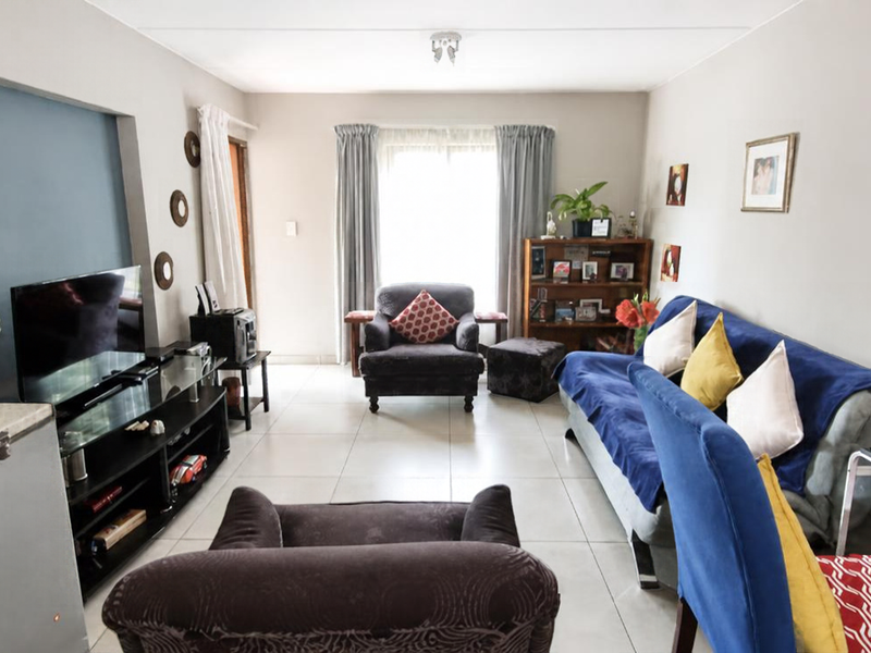 A comfortable living room featuring neutral walls, a blue accent wall, and tiled flooring, providing a functional and well-lit space.