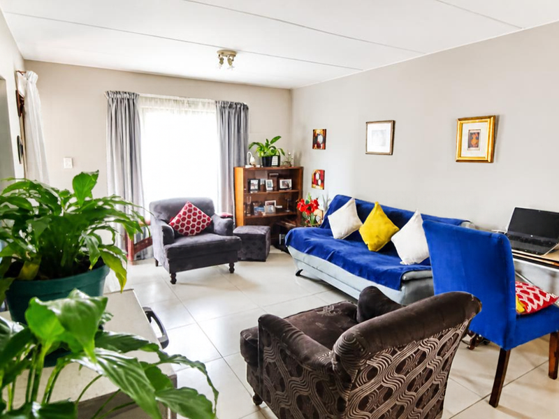 A spacious living room featuring neutral wall tones, a blue accent wall, and tiled flooring, offering a comfortable and versatile living area.