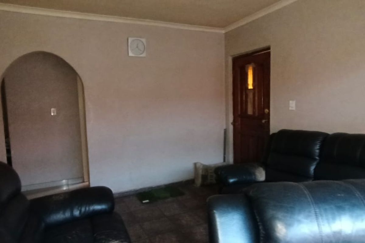 A living room featuring tiled flooring, an arched doorway leading to another area, and a timber entrance door.