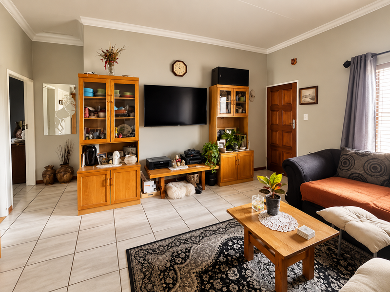 A comfortable living room featuring neutral wall tones, ceramic tiled flooring, and classic coved ceiling cornicing, providing a functional and well-maintained living space.