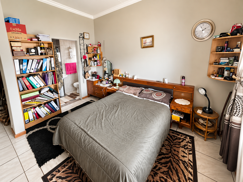 A bedroom featuring tiled flooring, a built-in headboard, and direct access to an en-suite bathroom.
