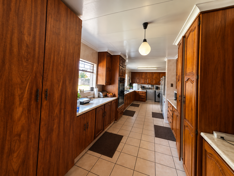 Spacious kitchen featuring extensive wooden cabinetry, stone countertops, built-in oven, and ceramic tile flooring in a functional galley layout.