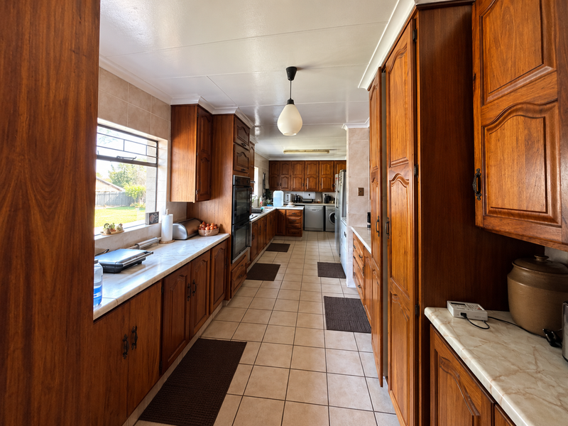 Spacious kitchen featuring extensive wooden cabinetry, laminate countertops, tiled flooring, and a functional layout with built-in oven and ample storage space.