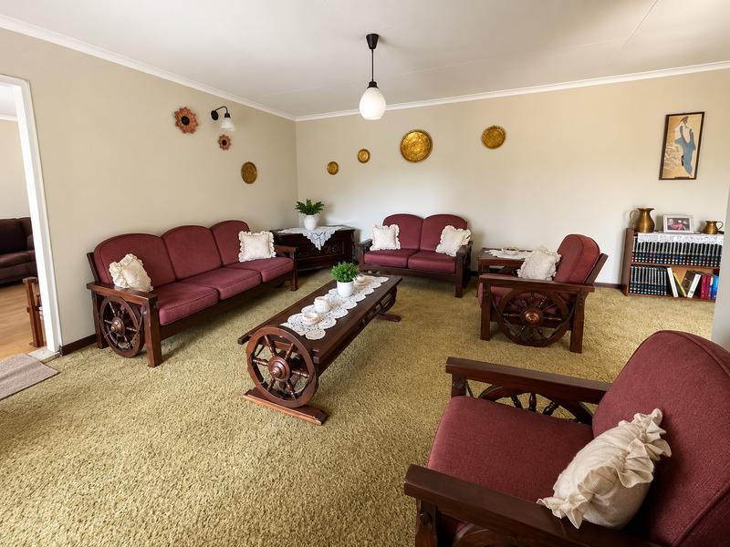 A spacious living room featuring neutral wall tones, carpeted flooring, and classic lighting fixtures, offering a comfortable and traditional living environment.