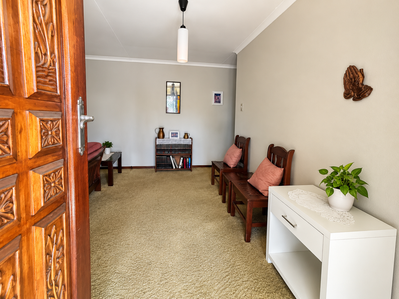 An entrance area featuring a decorative carved wooden door, neutral wall finishes, and carpeted flooring, providing a welcoming transition into the home.