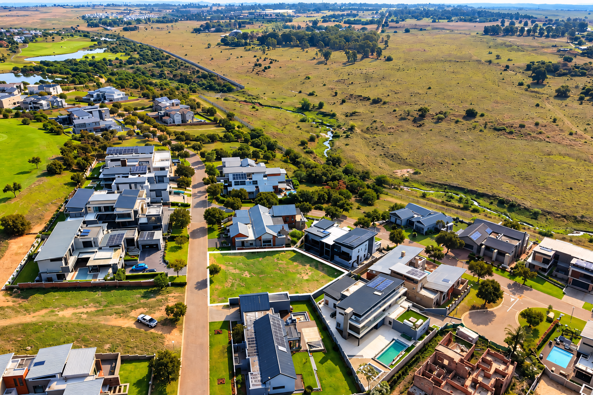 An aerial view of a modern residential estate featuring contemporary homes, swimming pools, solar installations, and proximity to a golf course and open landscape.