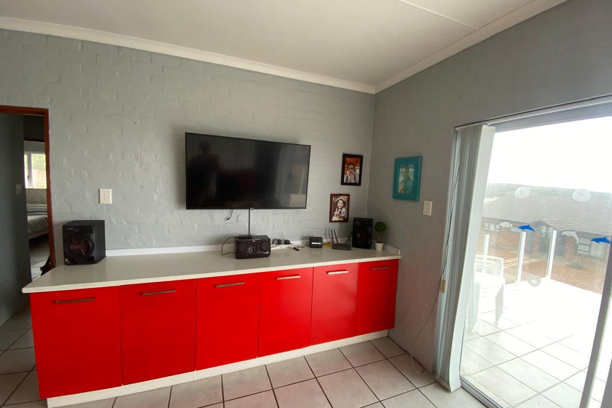 Living area featuring built-in red cabinetry, tiled flooring, and sliding glass doors providing access to an outdoor patio.