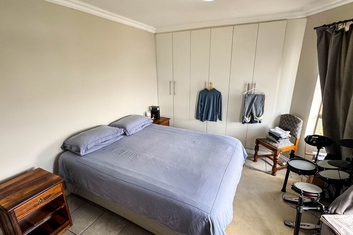 A bedroom featuring built-in floor-to-ceiling wardrobes, tiled flooring, and crown molding, providing ample storage space.