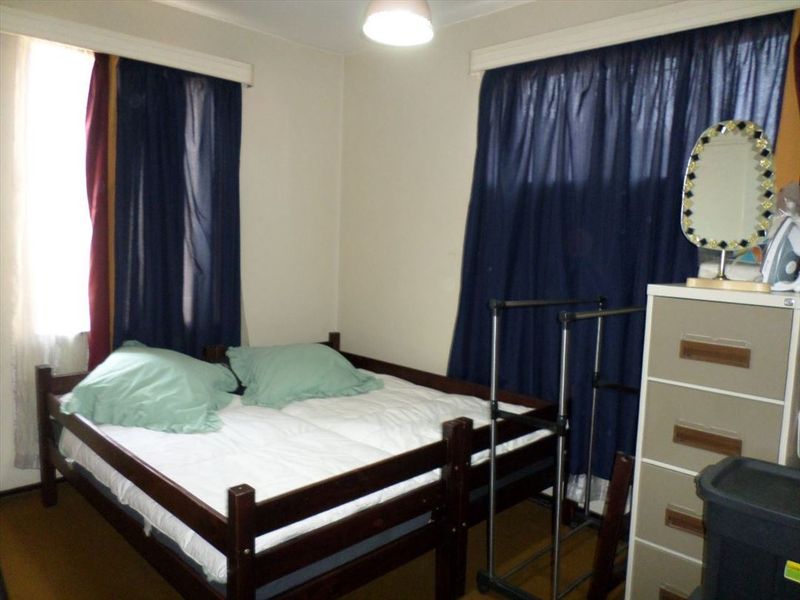 A standard bedroom featuring neutral walls, carpeted flooring, and dual window treatments.