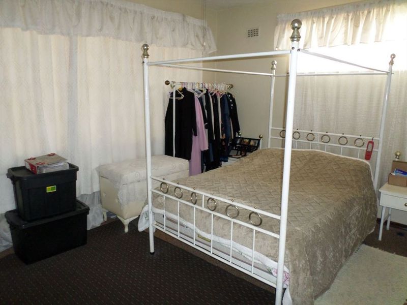 A bedroom featuring carpeted flooring and window treatments, offering a functional space ready for personalization and updates.