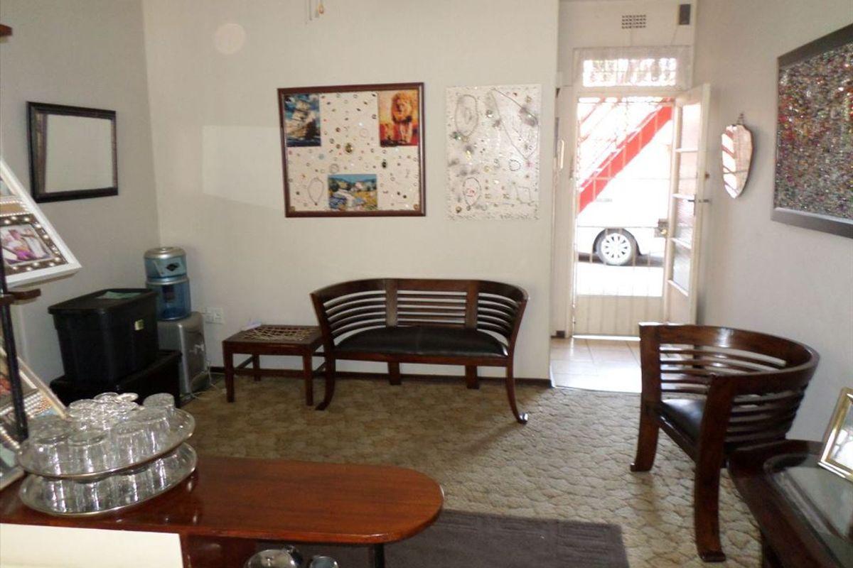 A living room area featuring carpeted flooring and direct access to an exterior entrance with a security gate.