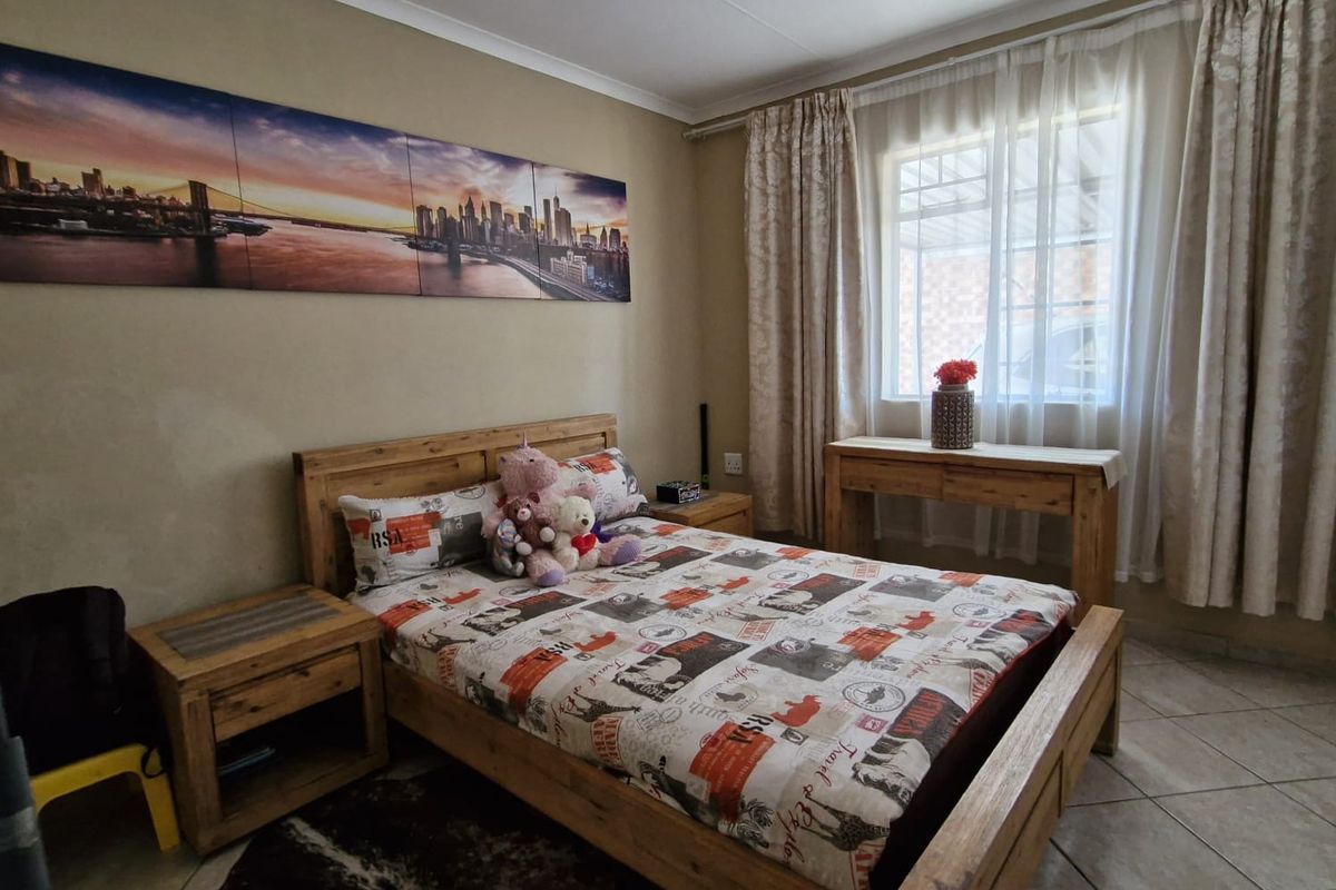 A bedroom featuring tiled flooring and natural light through a window with curtain rails.