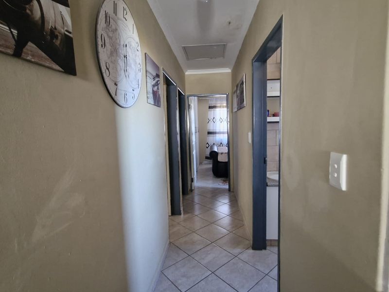 A functional hallway featuring tiled flooring and a ceiling access hatch, connecting multiple rooms within the home.