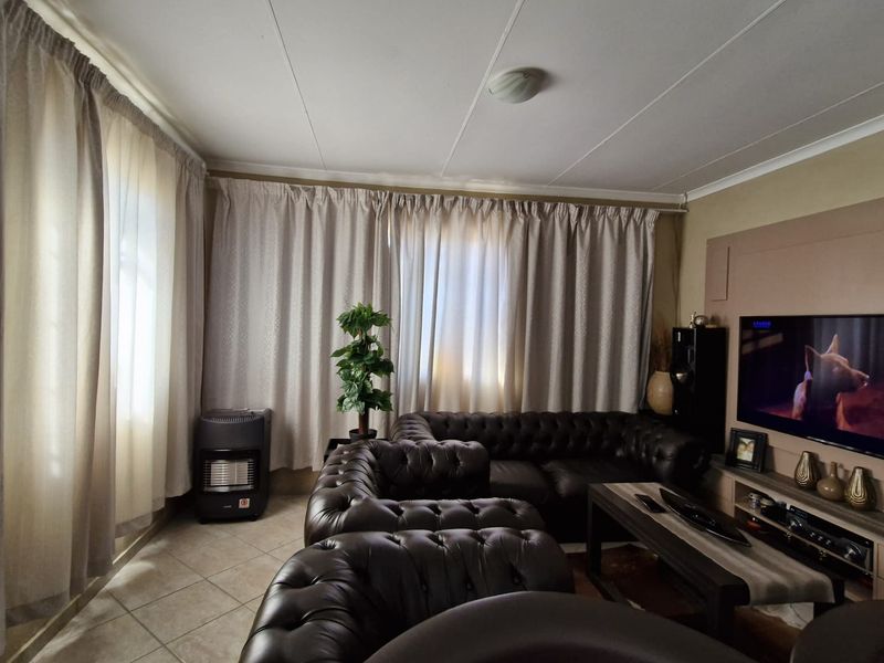 A comfortable living room featuring tiled flooring and a dedicated wall-mounted entertainment area, offering a functional space for relaxation.