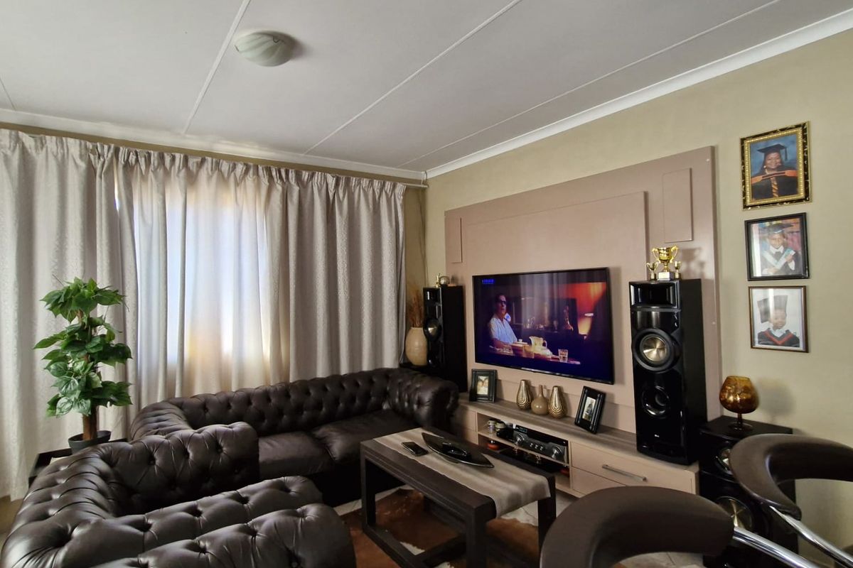 A comfortable living room featuring a built-in media wall unit, tiled flooring, and neutral wall tones, providing a functional space for relaxation.