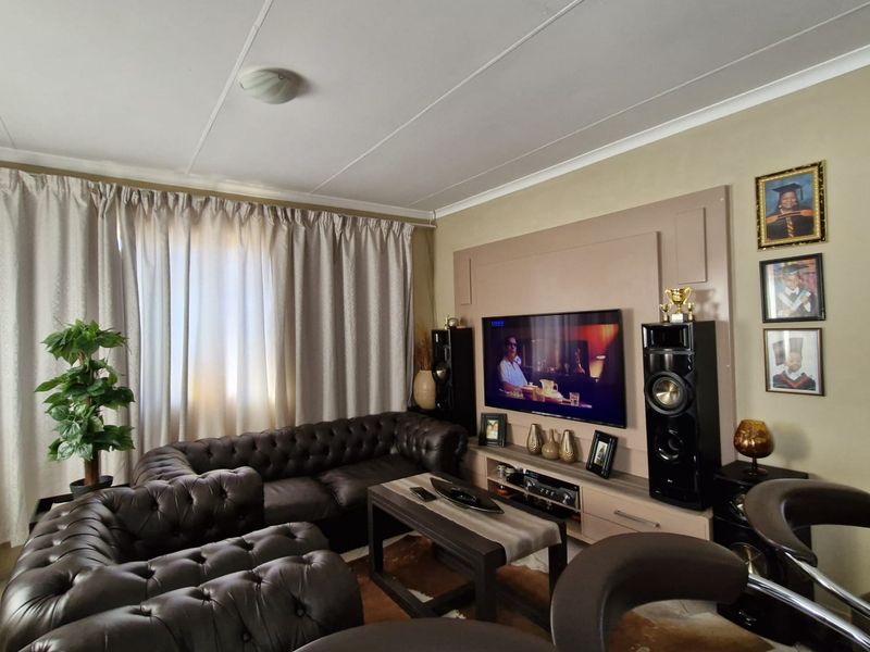 A comfortable living room featuring a built-in media wall unit, tiled flooring, and neutral wall tones, providing a functional space for relaxation.