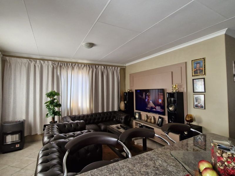 Open-plan living area featuring a built-in media wall, granite kitchen countertop, and tiled flooring, creating a functional and connected living space.