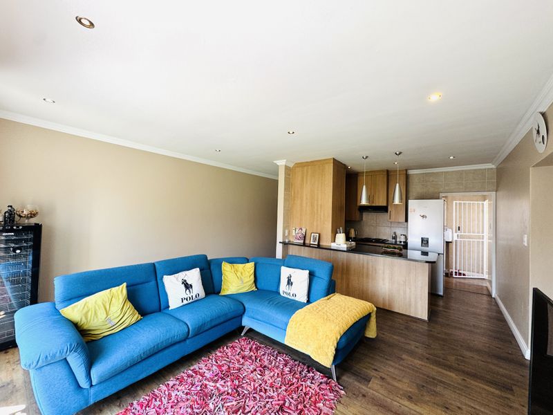 An open-plan living area featuring laminate flooring, recessed lighting, and a functional kitchen with granite countertops and a breakfast bar.