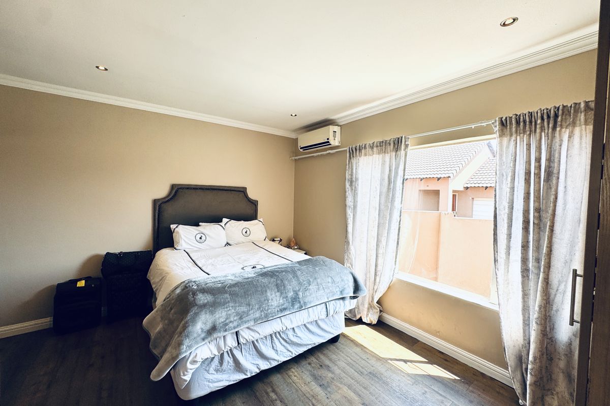 A well-maintained bedroom featuring laminate flooring, crown molding, recessed lighting, and a wall-mounted air conditioning unit.