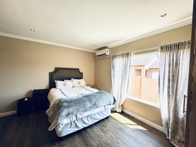 A well-maintained bedroom featuring laminate flooring, crown molding, recessed lighting, and a wall-mounted air conditioning unit.
