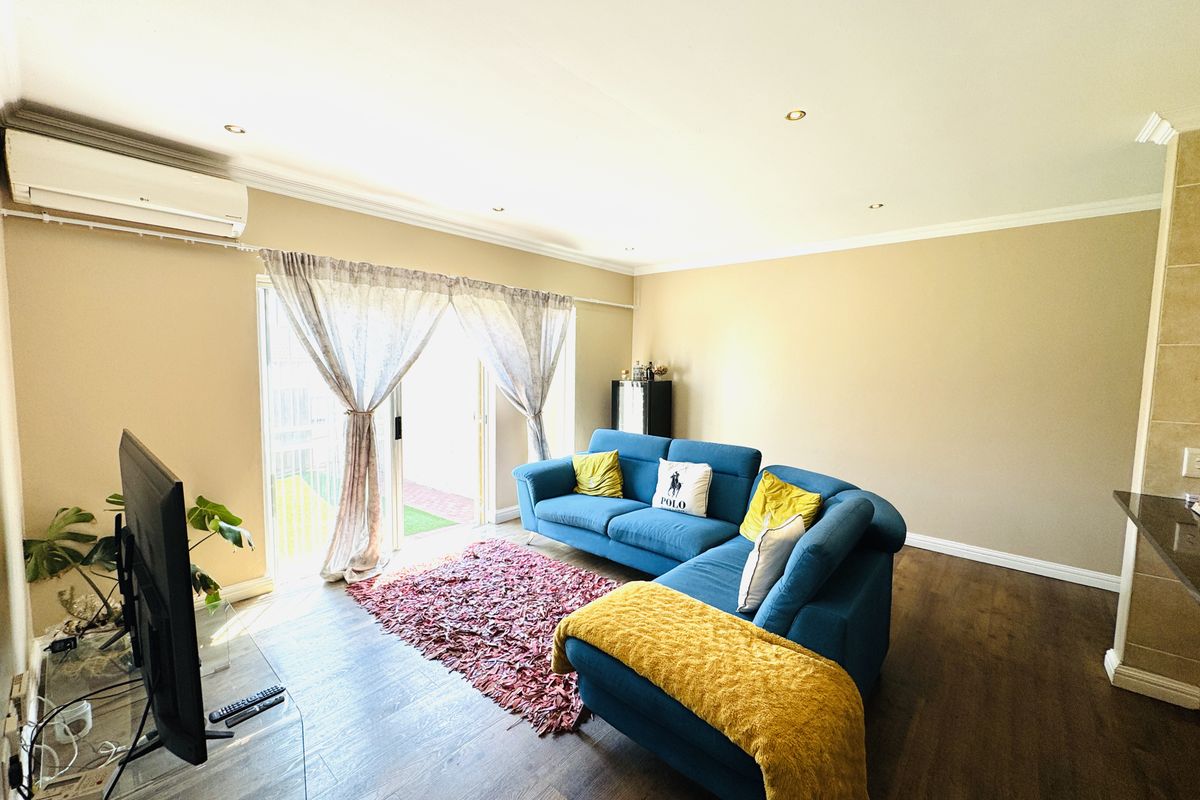 A bright living room featuring laminate flooring, recessed downlights, and a sliding glass door providing access to the outdoor area.