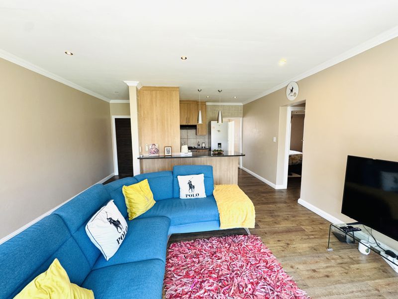 Open-plan living area featuring laminate flooring, recessed lighting, and a functional kitchen with a breakfast bar, creating a cohesive and versatile living space.