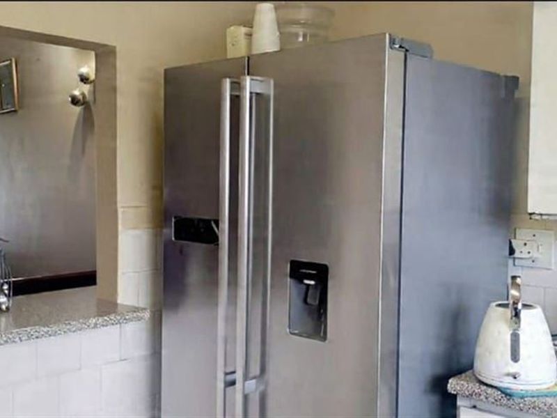 A functional kitchen area featuring granite countertops, tiled backsplash, and a convenient pass-through window connecting to the adjacent living space.