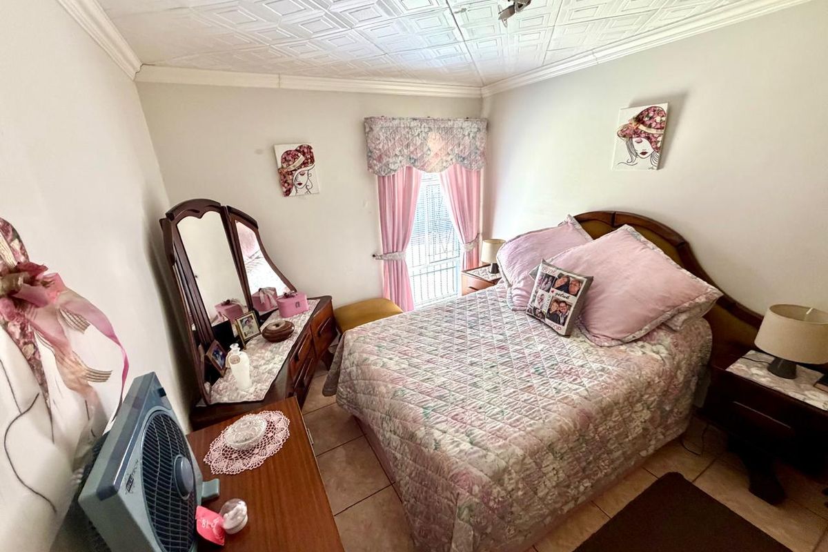 A bedroom featuring tiled flooring and decorative ceiling tiles, with a security gate installed on the window.