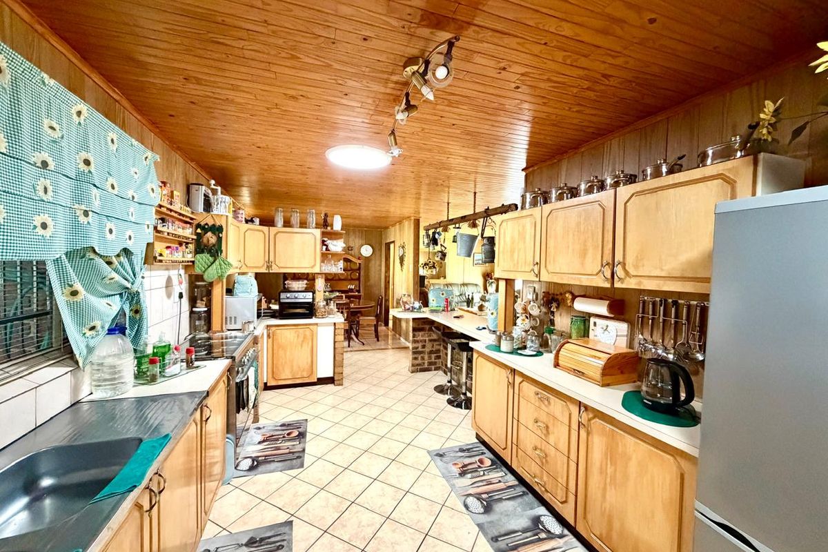 Spacious kitchen featuring extensive wooden cabinetry, tiled flooring, a breakfast bar, and a warm wooden ceiling finish.