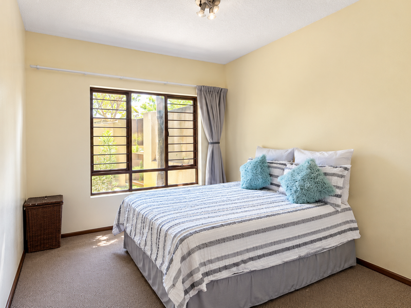 A functional bedroom featuring carpeted flooring, neutral wall finishes, and a window equipped with security bars for added peace of mind.