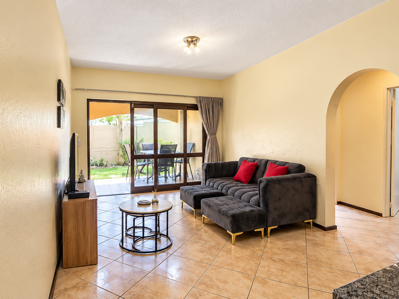 Open plan living area featuring tiled flooring, an arched entryway, and sliding glass doors providing access to an outdoor patio space.