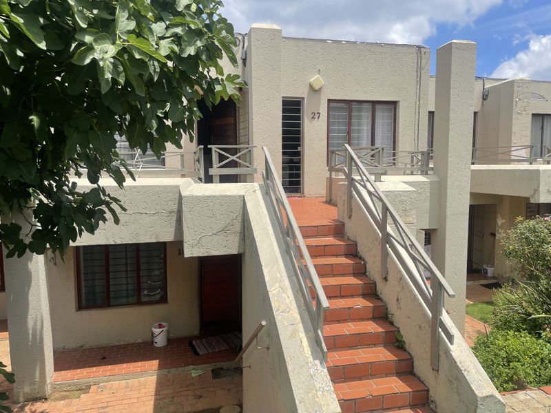 Exterior view of an apartment unit featuring a terracotta tiled staircase with metal railings and a security gate entrance.